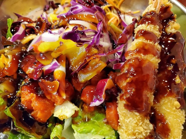 Poke bowl with spicy tuna and tempura shrimp. Cabbage, salad / rice mix, crab salad.